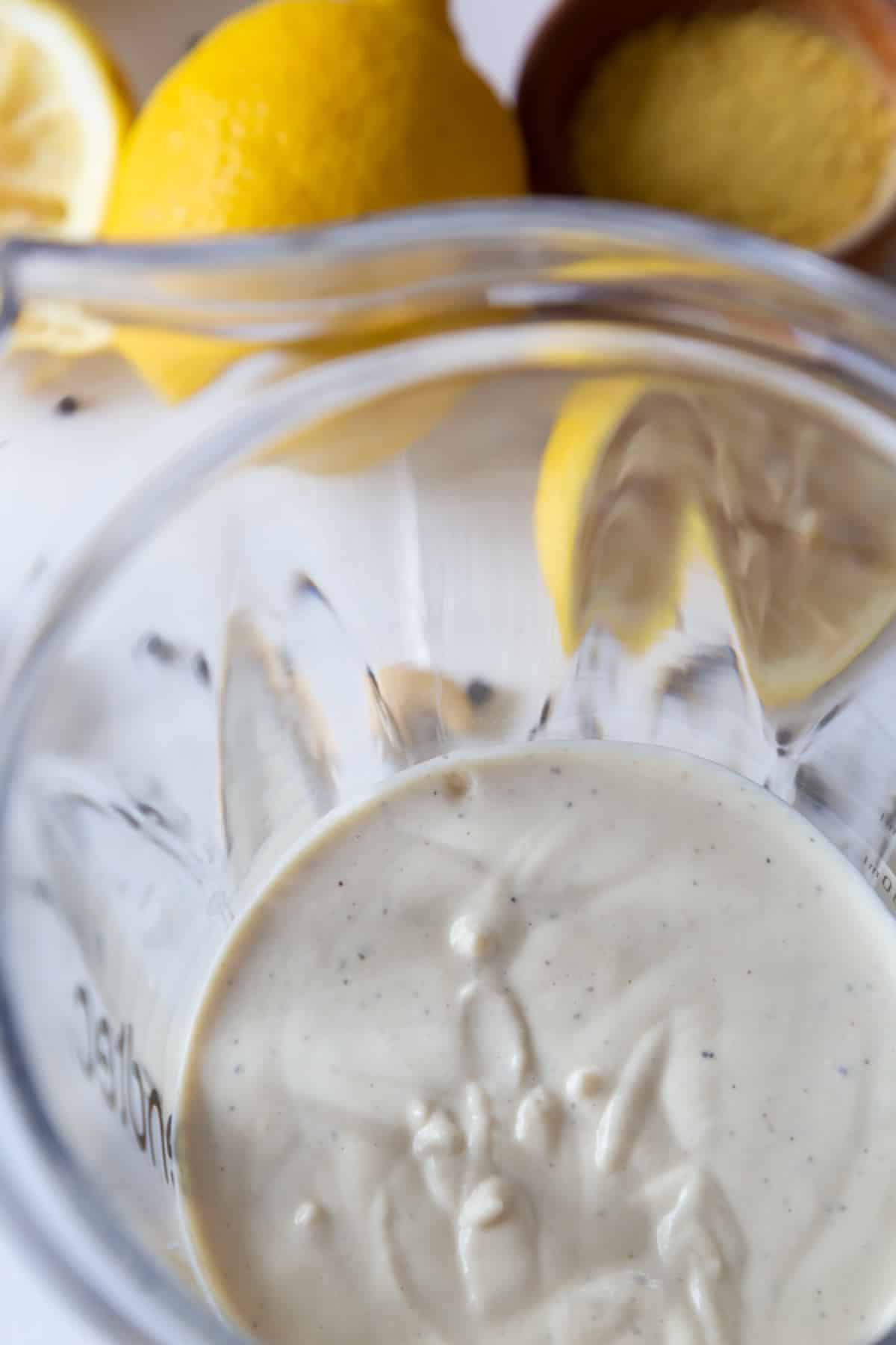 Alfredo sauce in a blender with lemons next to the blender.