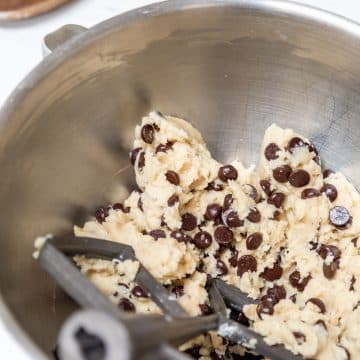 A silver mixing bowl with chocolate chip cookie dough.