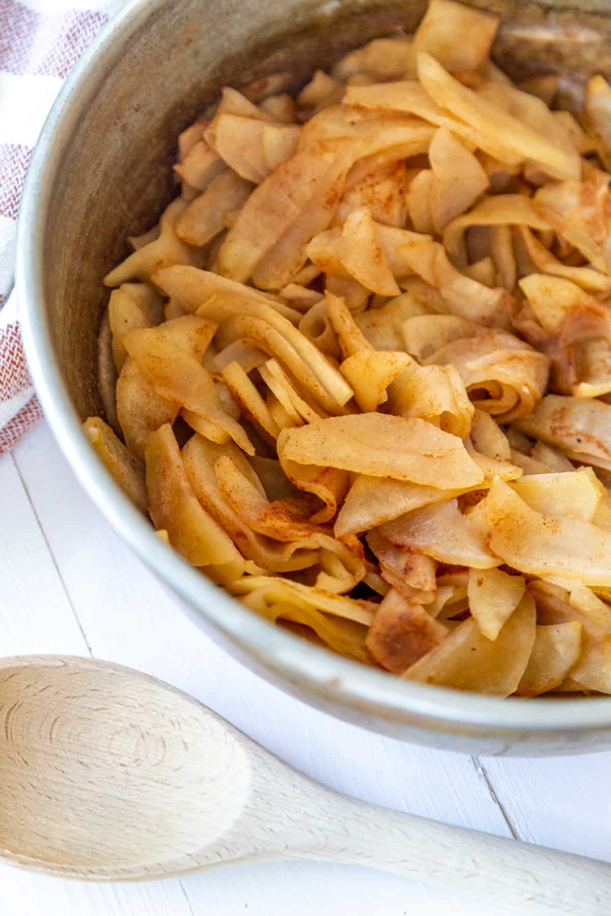 A pot of chunky applesauce with a wooden spoon next to the pot.