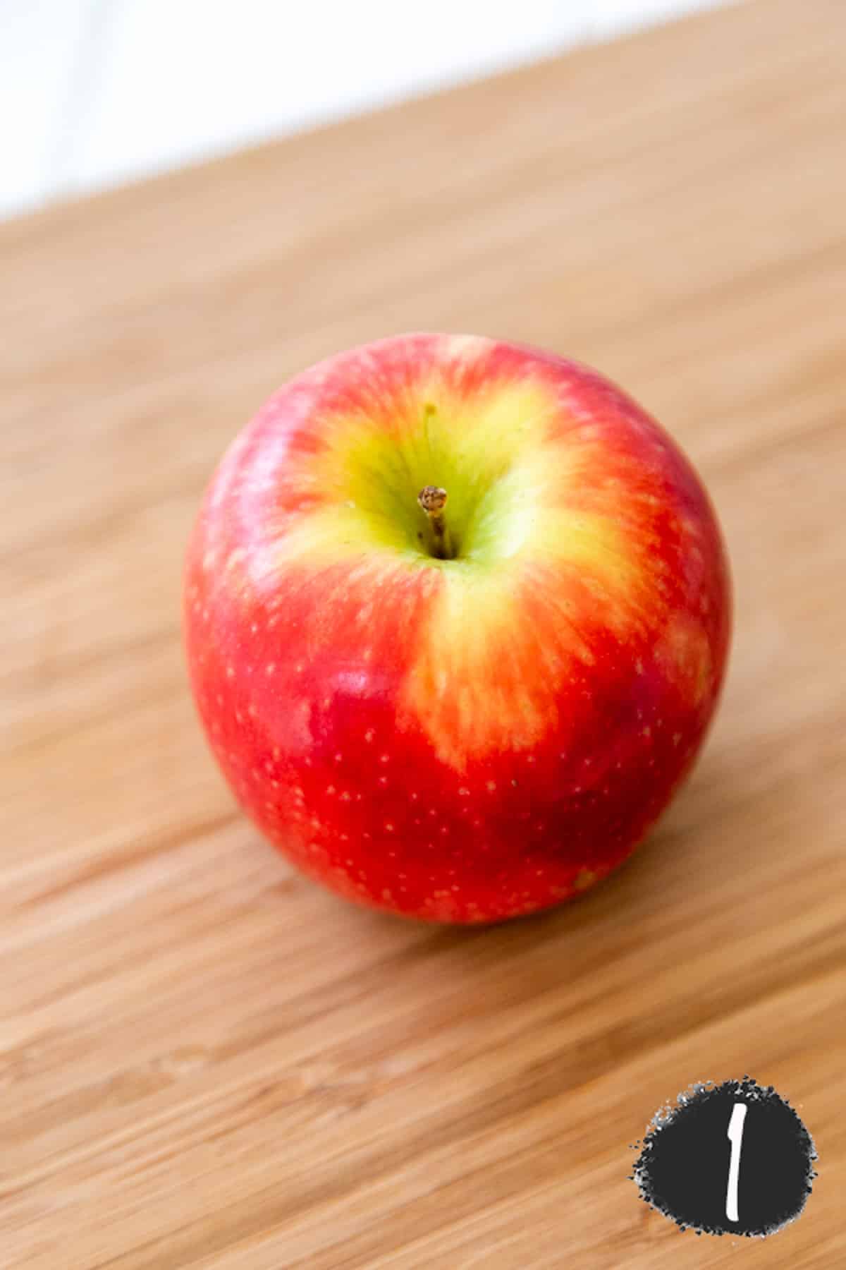 A red apple on a wooden board.