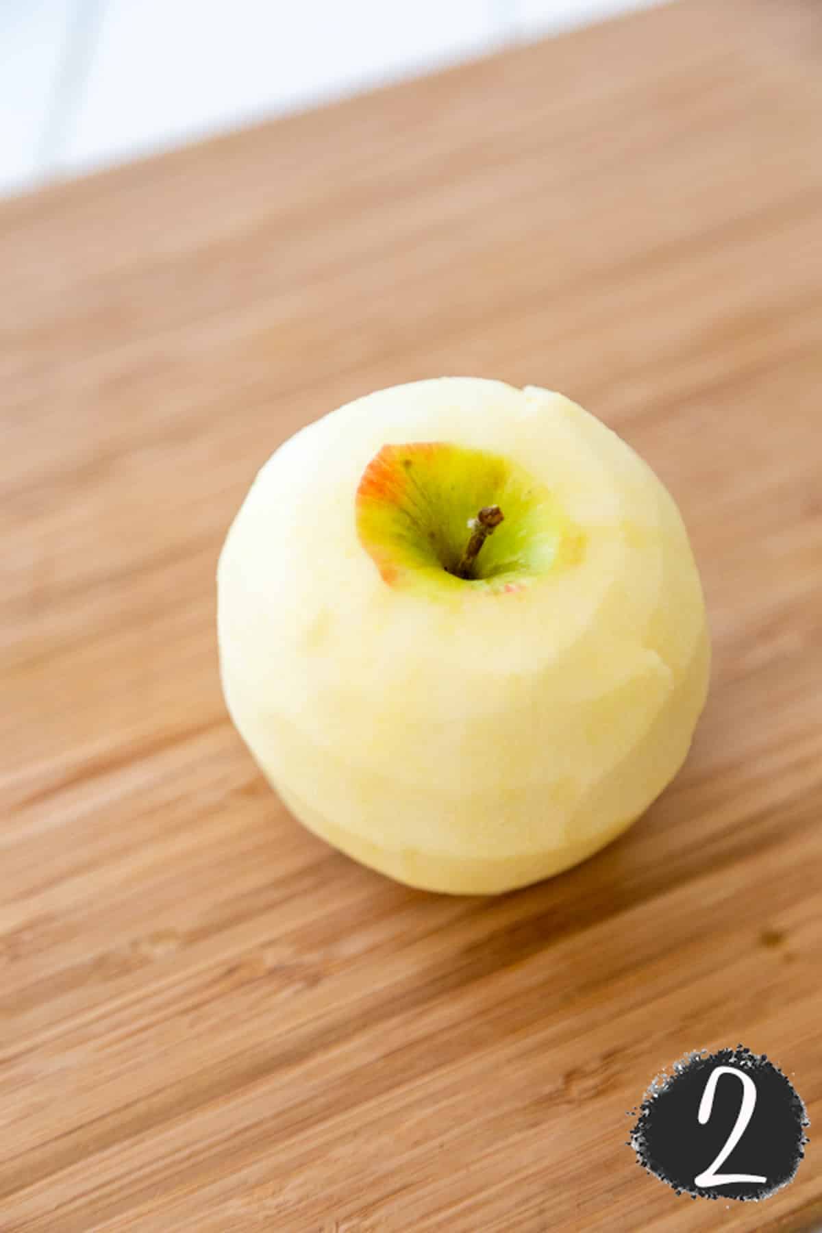 A whole peeled apple on a wooden board.