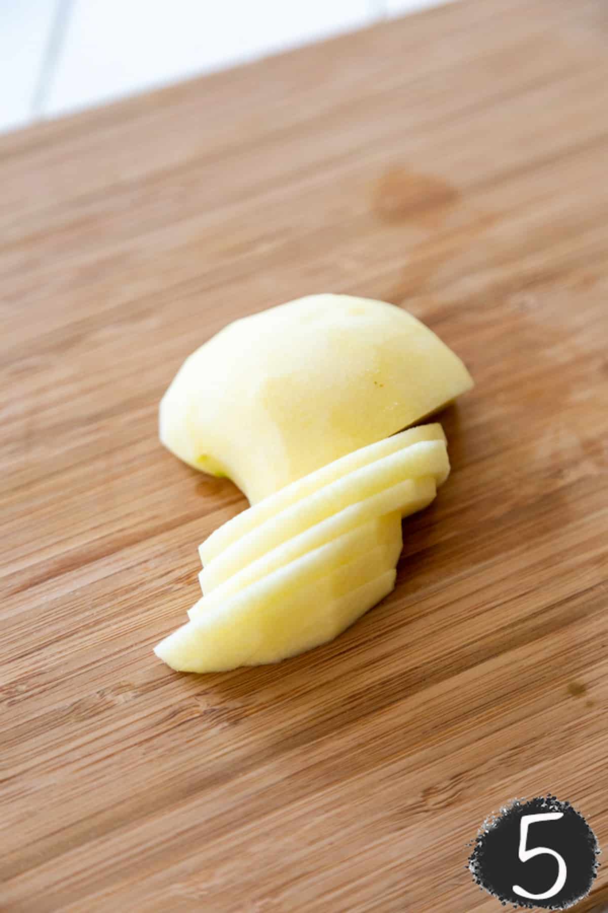 Peeled apple slices on a wooden board.