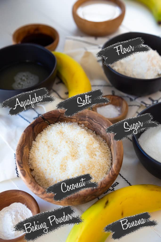 A picture of ingredients for vegan banana cake with the ingredients in wooden bowls and black measuring cups.