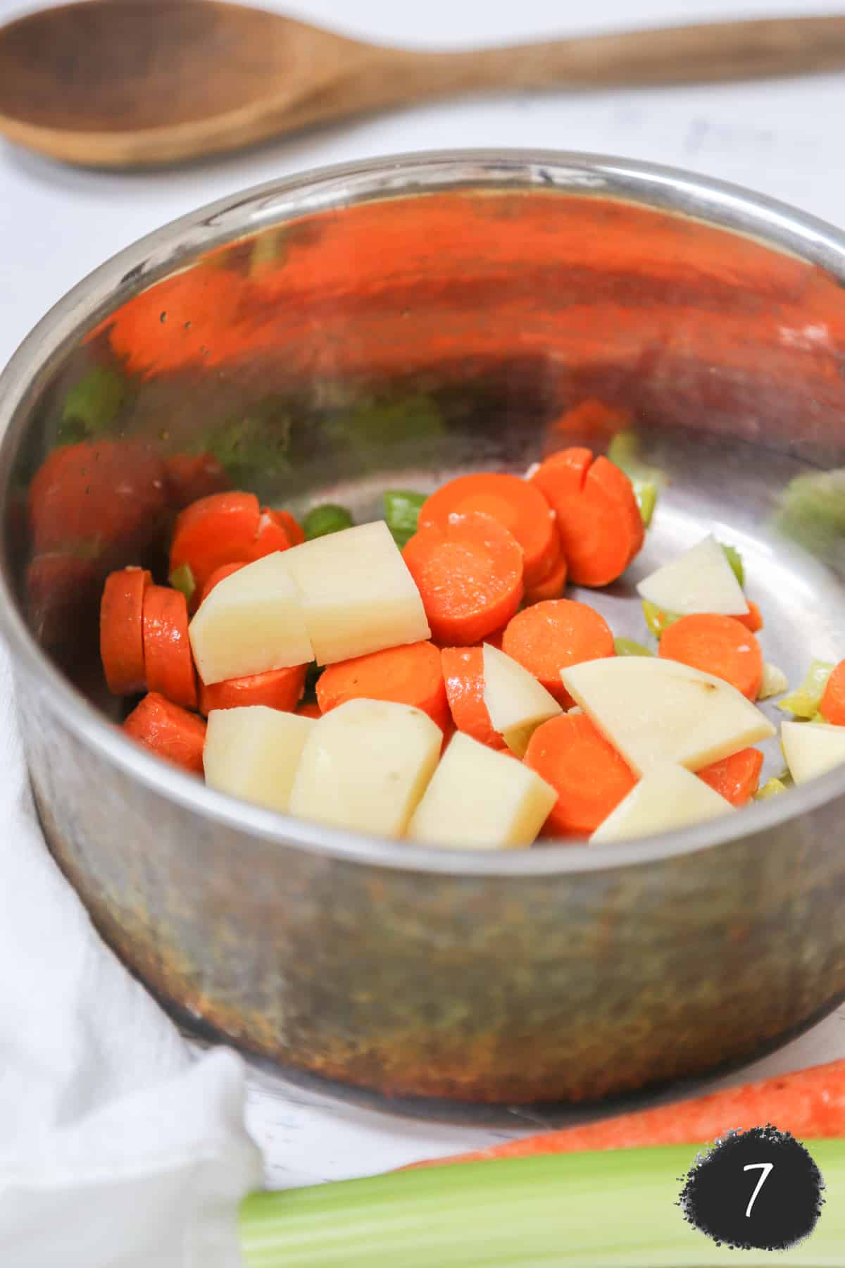 Diced potato, carrot, and celery in a copper pot.