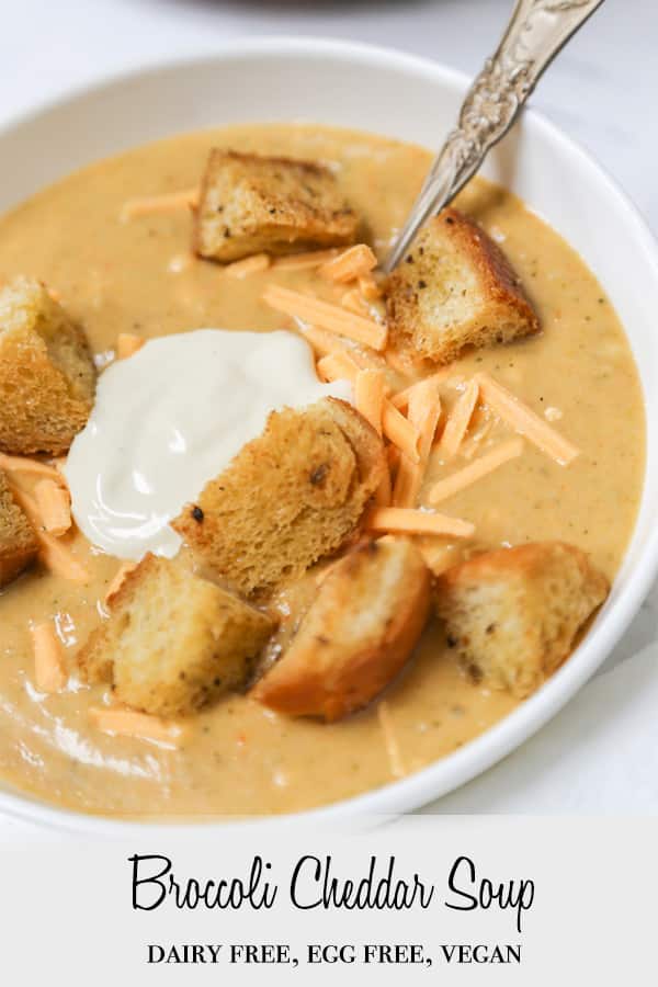 A Pinterest pin for vegan broccoli cheddar soup with a close up picture of the soup in a bowl with croutons on top.