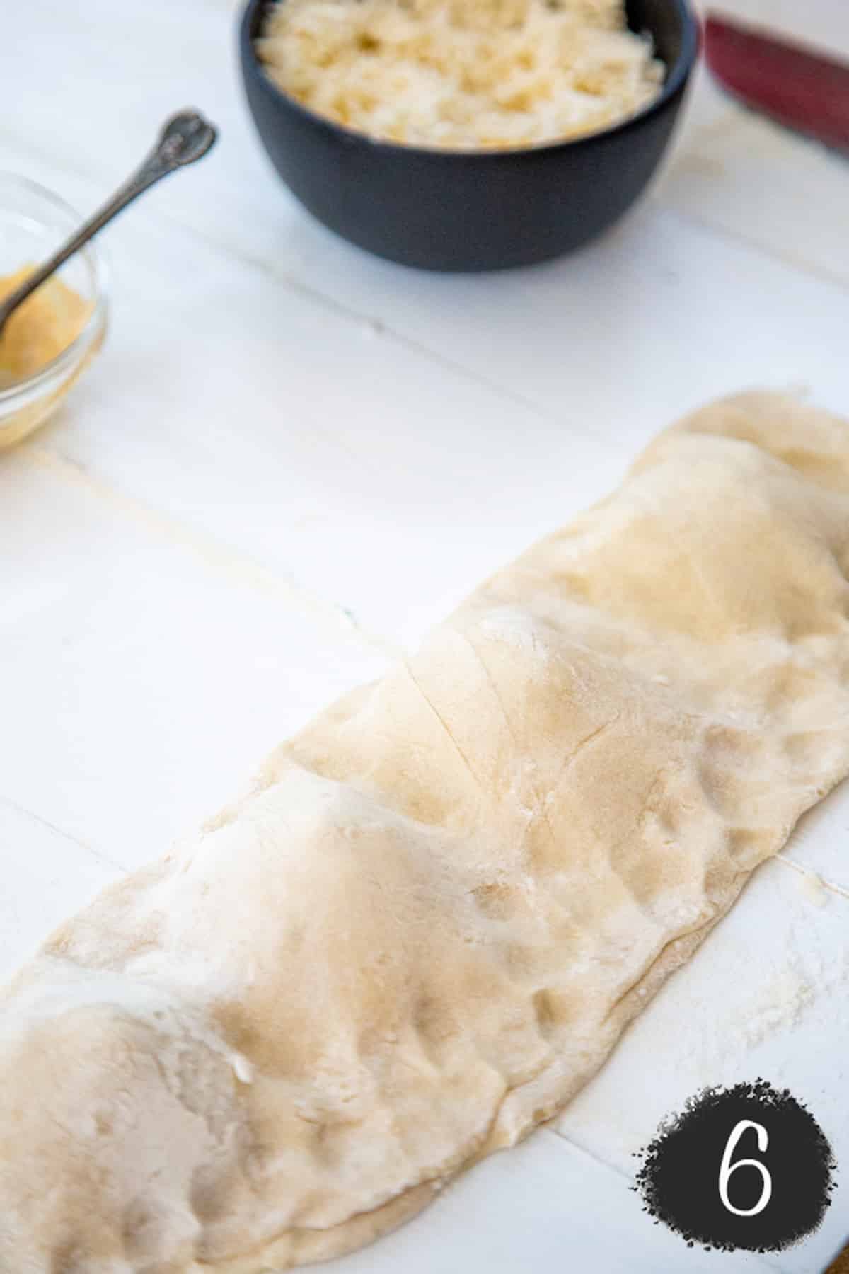 Pizza dough folded over vegan calzone filling with pinched edges to keep the filling in the dough.