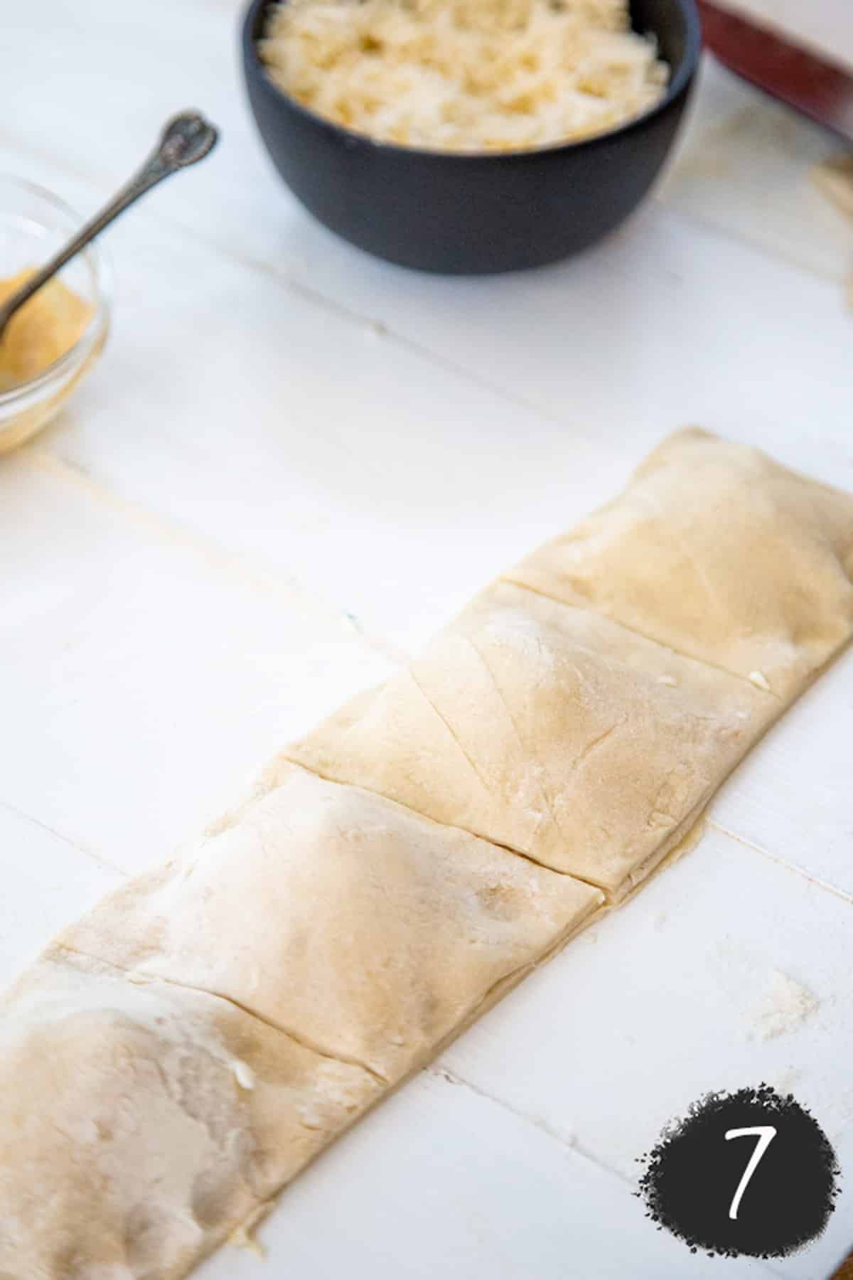 A log of pizza dough filled with calzone filling that's been sliced into individual squares.
