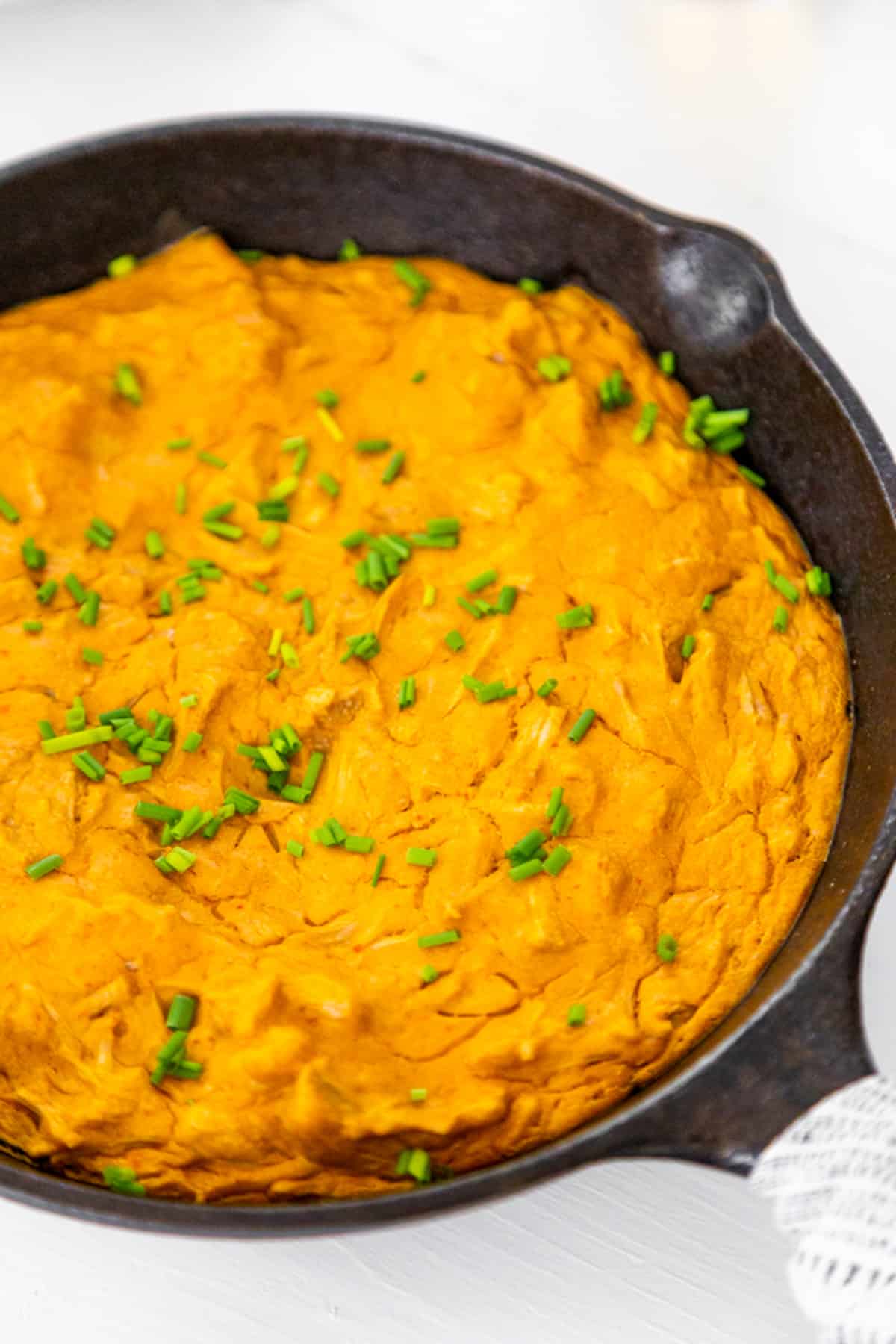 A cast iron skillet with baked buffalo chicken dip. 