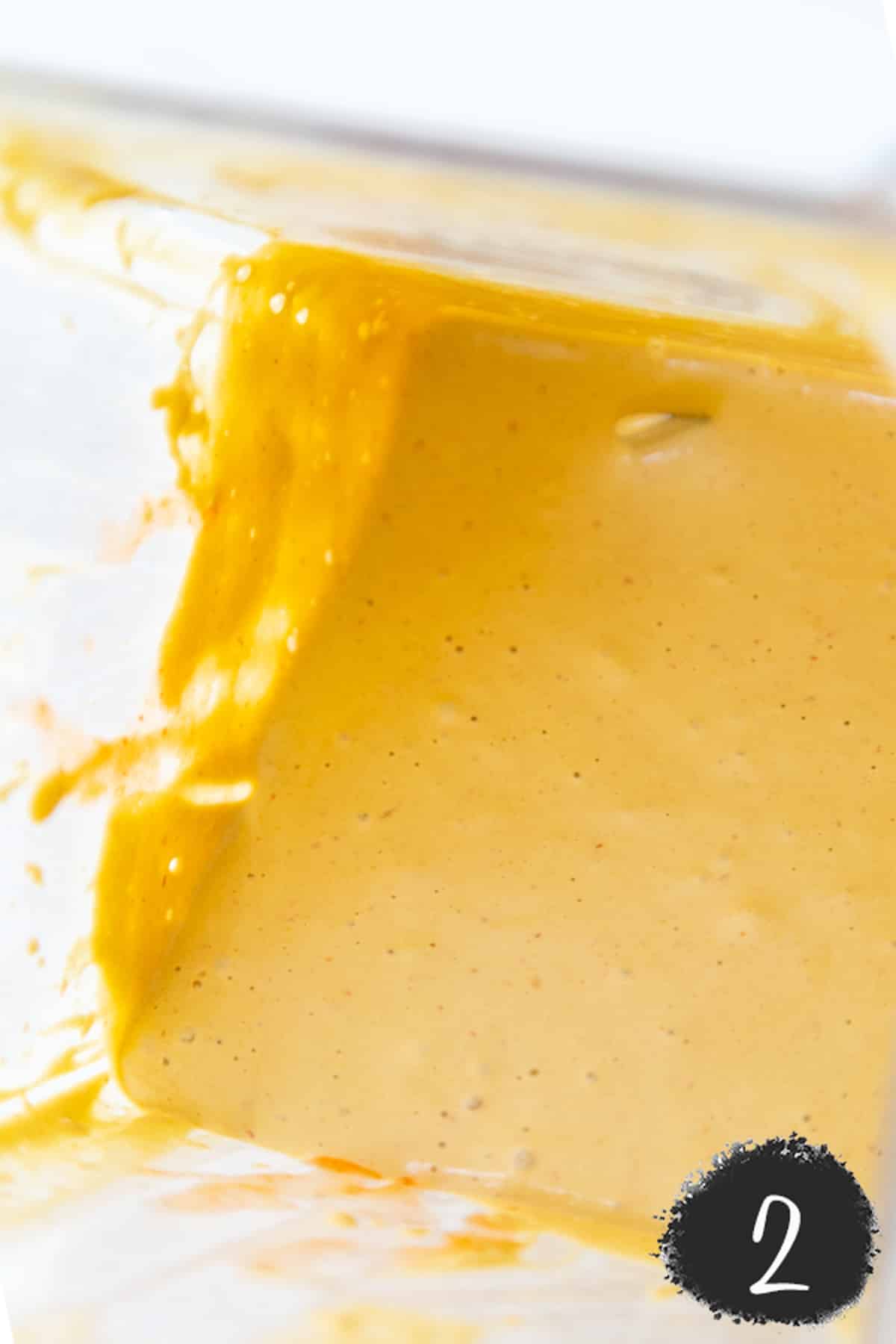 A blender with a thick orange cream sauce.