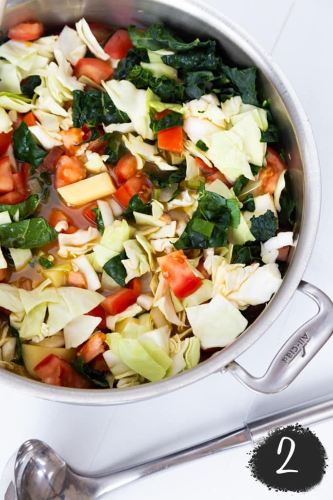 A soup pot with vegetables and chopped cabbage.