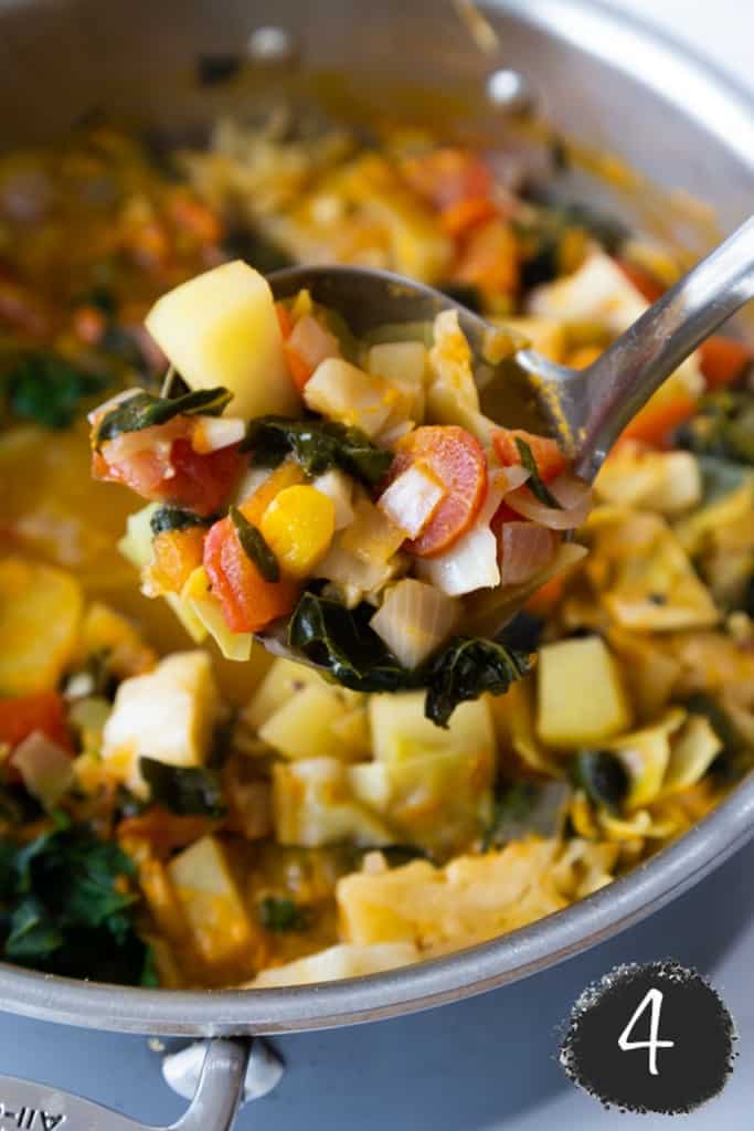 A ladle of cabbage soup held above the pot of soup.