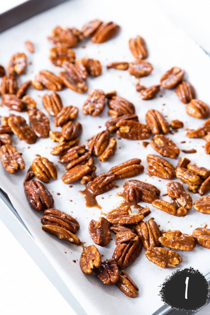 Whole pecans on a parchment paper lined baking sheet.