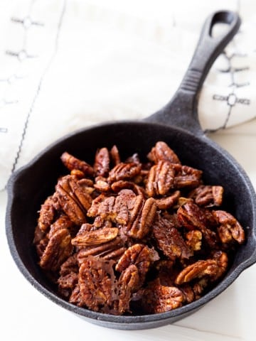 A cast iron skillet filled with cinnamon pecans.