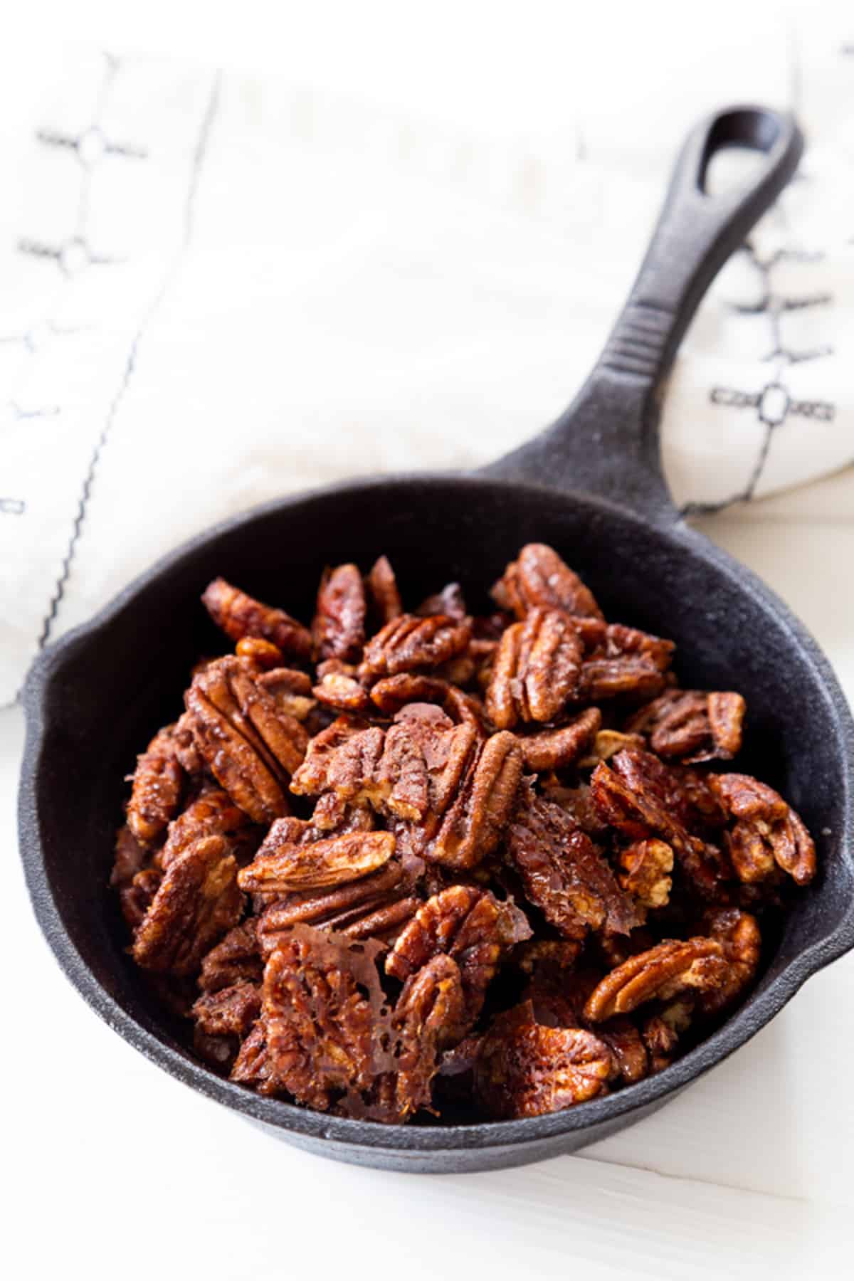A cast iron skillet filled with cinnamon pecans.