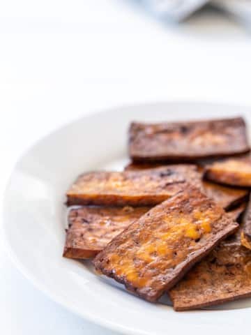 A white plate with tofu bacon.