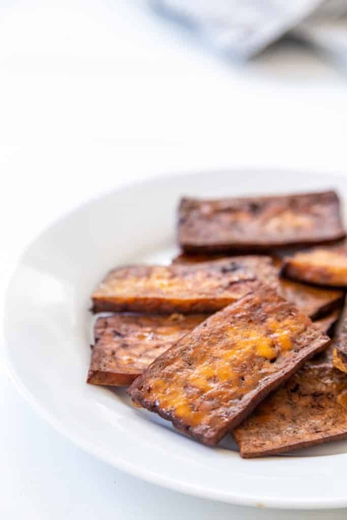 A white plate with tofu bacon.