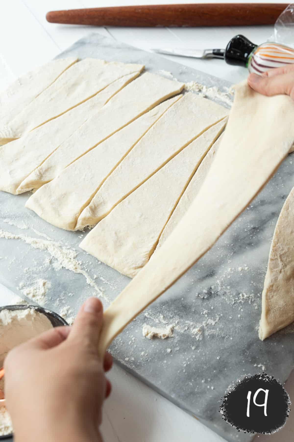 2 hands stretching a triangle of dough.