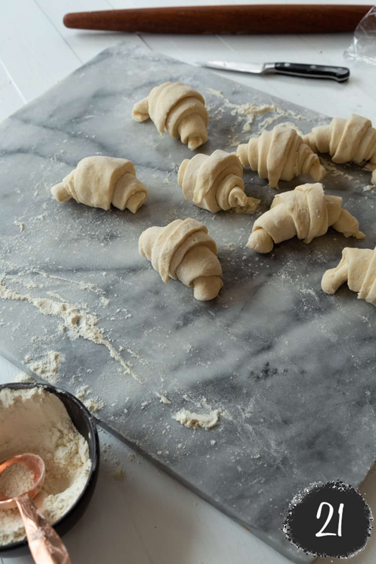 Unbaked croissants on a marble board.
