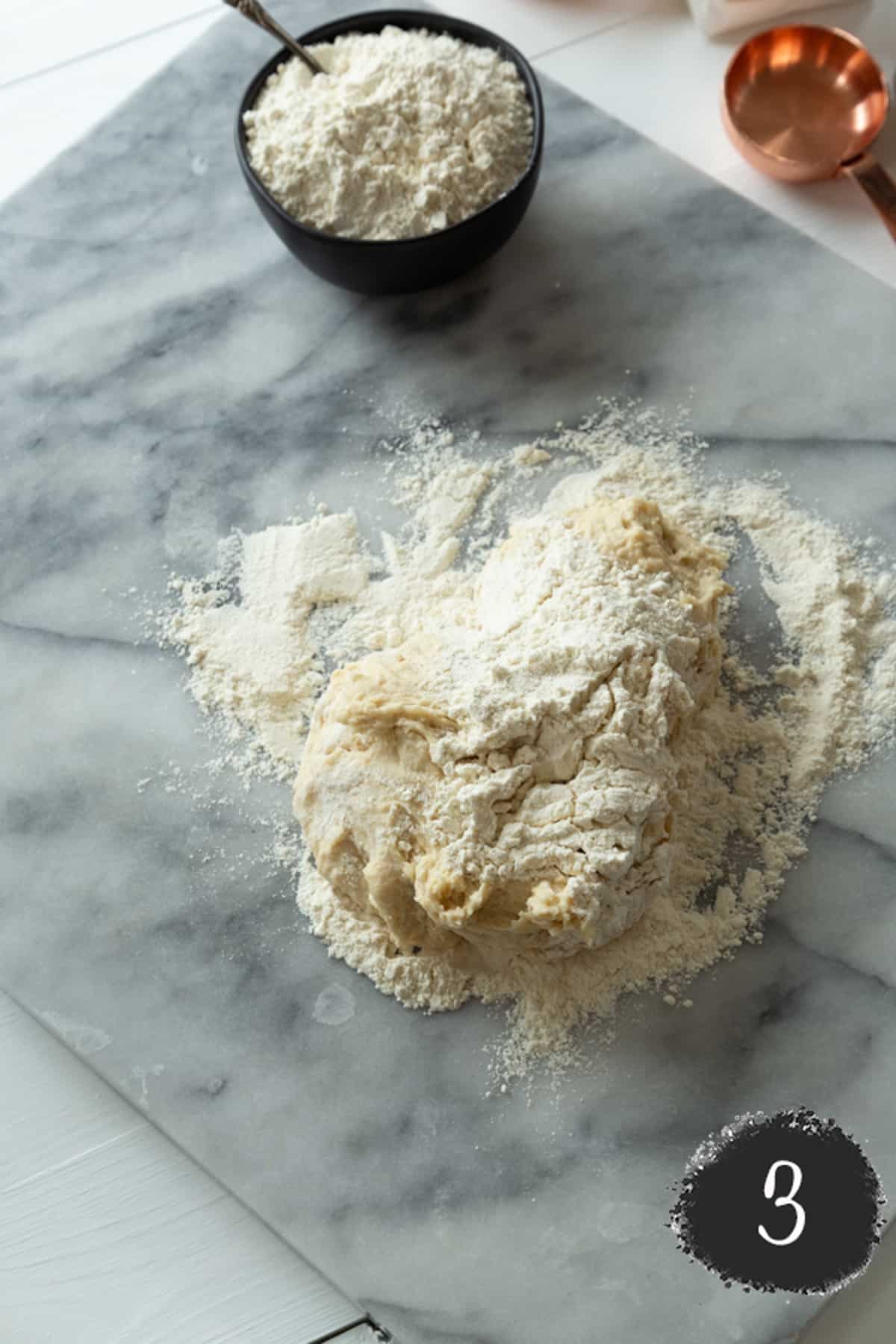 Croissant dough sprinkled with flour on a marble board.