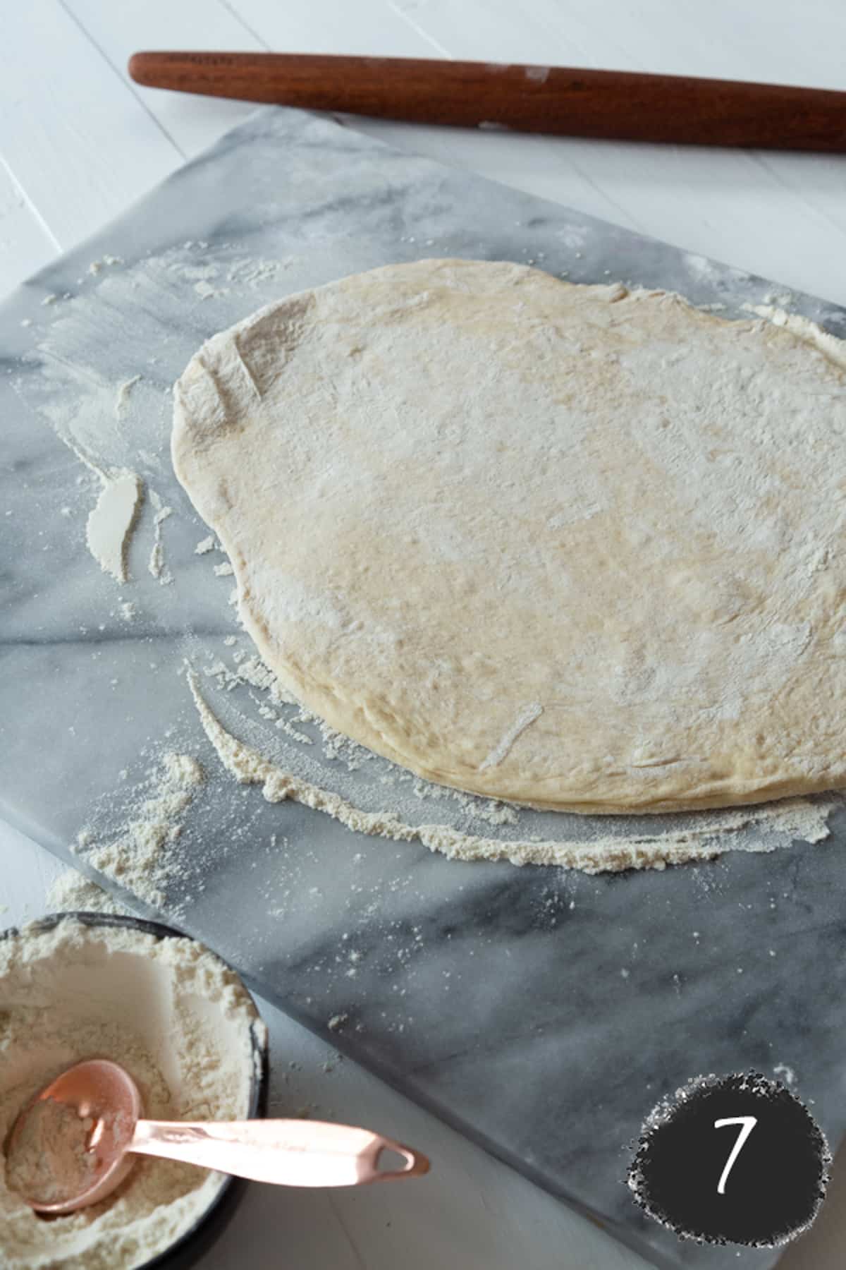 Croissant dough rolled out on a marble surface.