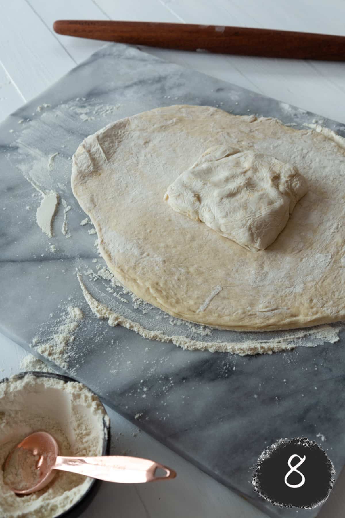 Rolled out croissant dough with a block of butter in the center of the dough.