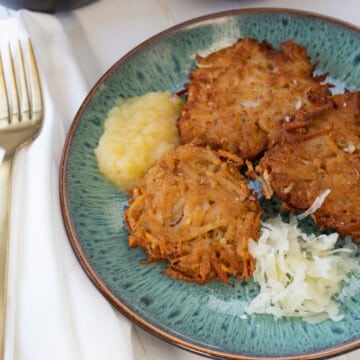A blue plate with potato pancakes and apple sauce.
