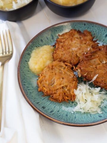 A blue plate with potato pancakes and apple sauce.