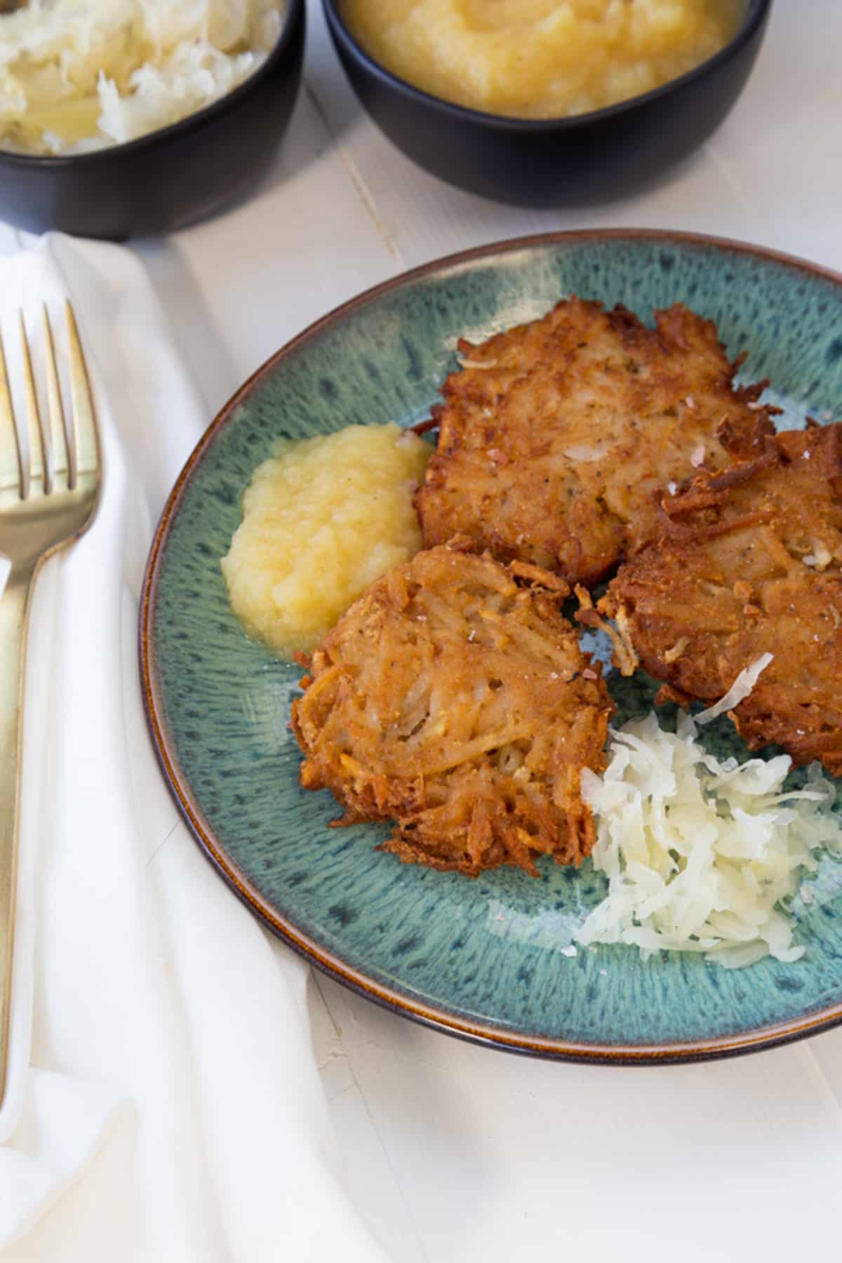 A blue plate with potato pancakes and apple sauce.