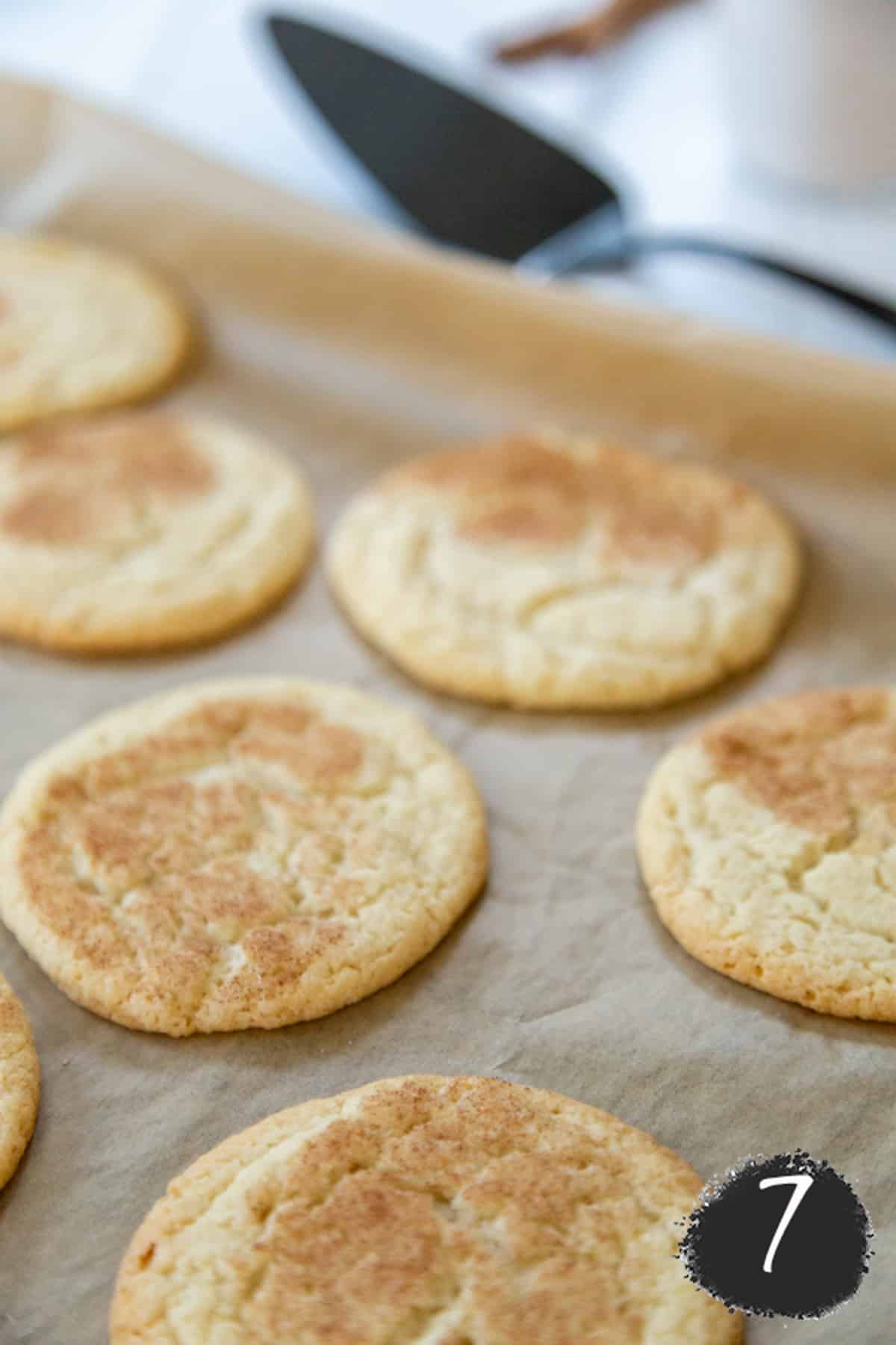 Baked snickerdoodles on a baking sheet.