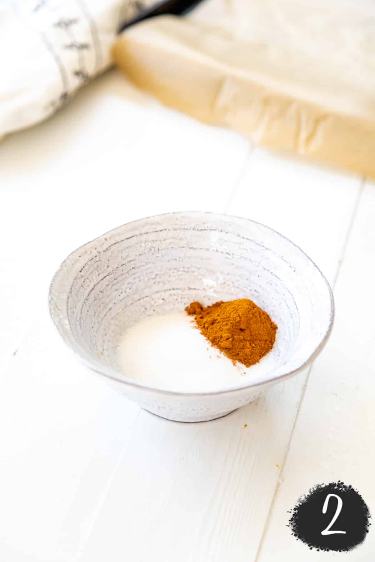 A white bowl with sugar and cinnamon.