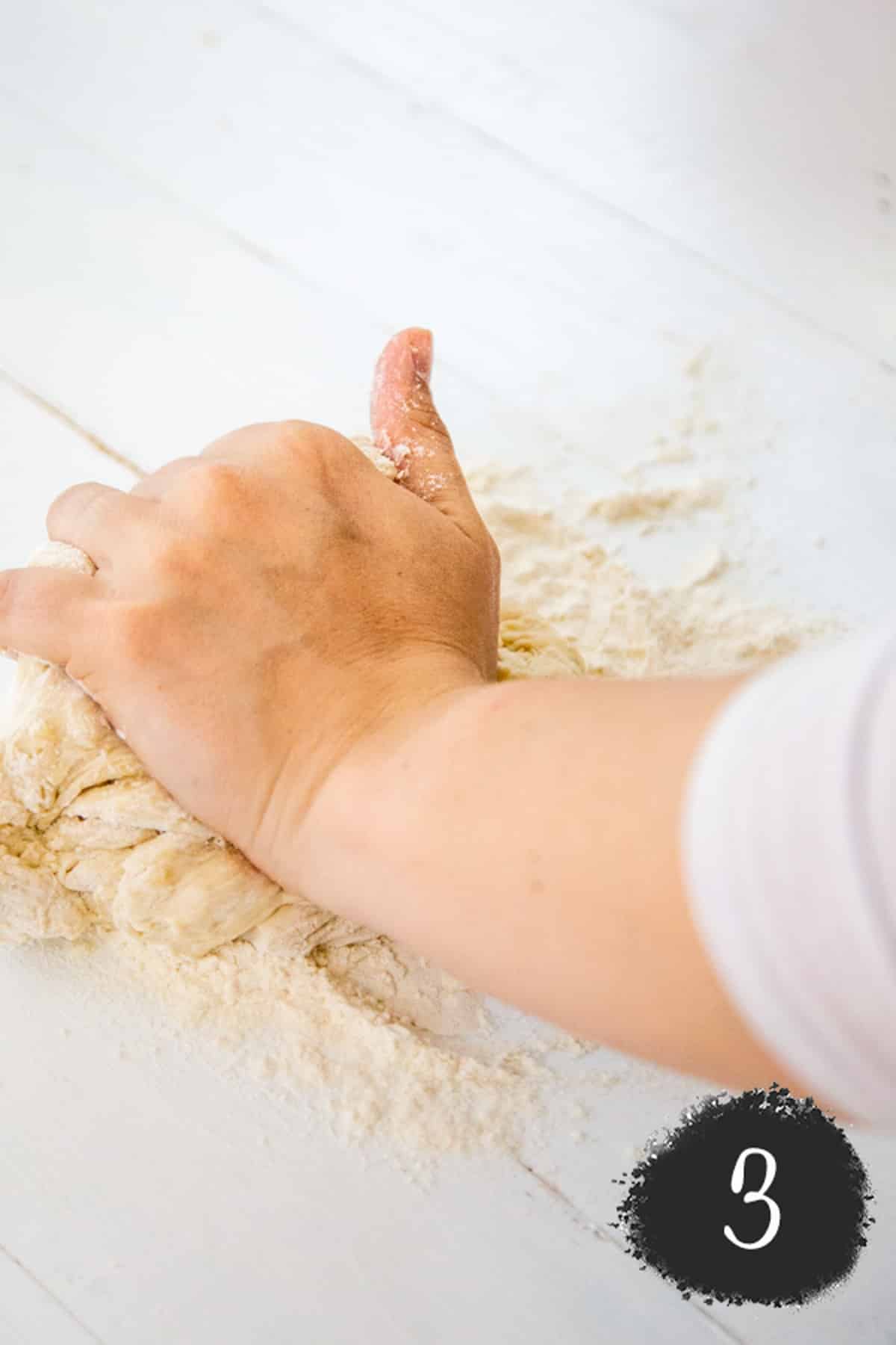A hand kneading pizza dough.