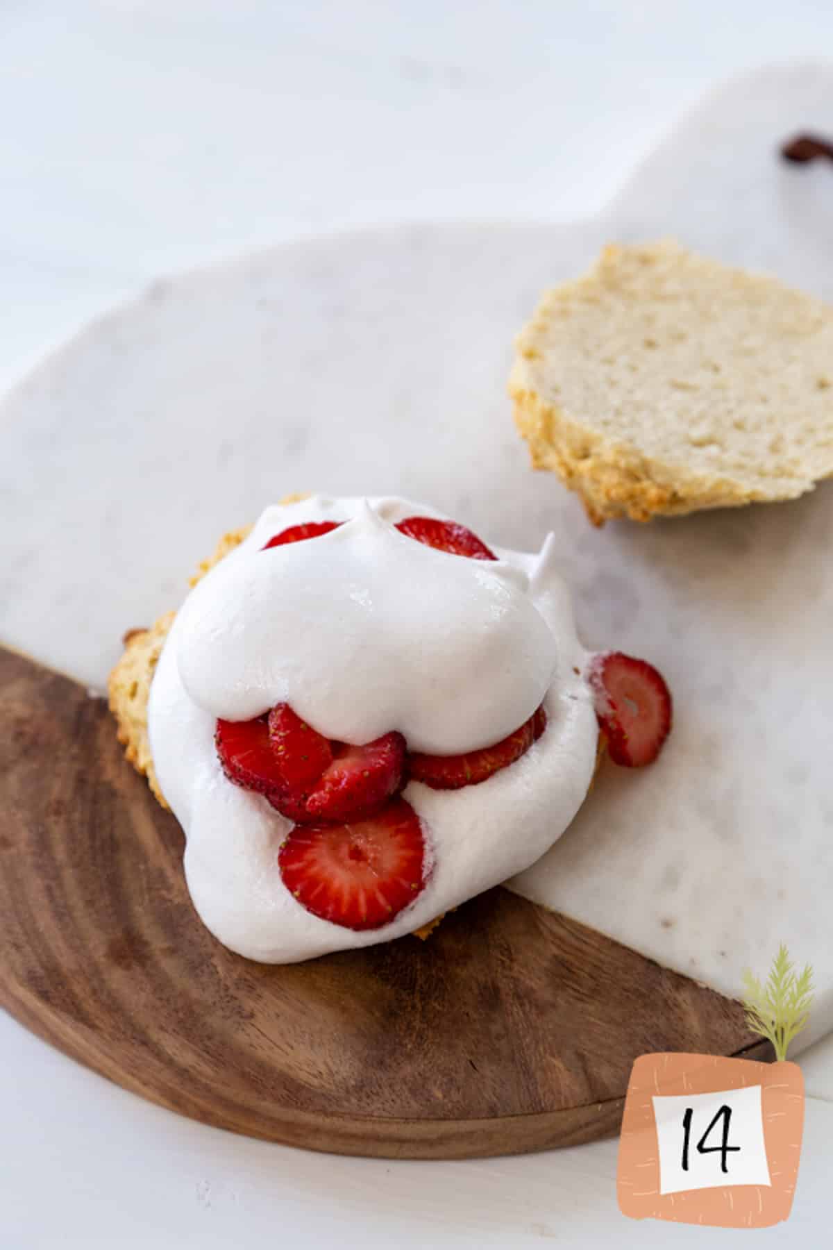 A sliced biscuit with strawberries and whipped cream.
