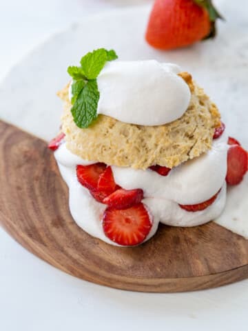 Strawberry shortcake with whipped cream on a wooden board.