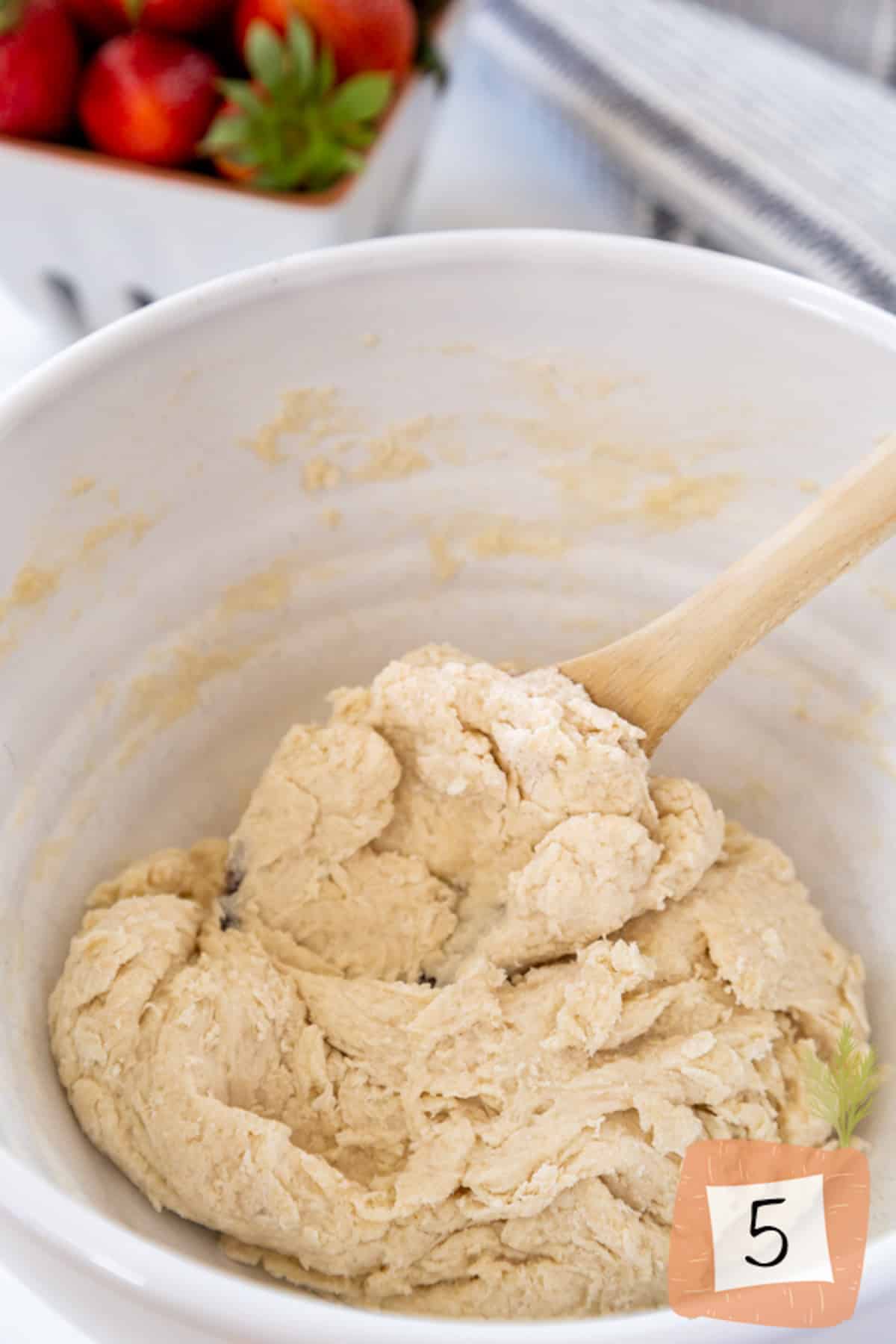 A wooden spoon stirring vegan shortcake dough.