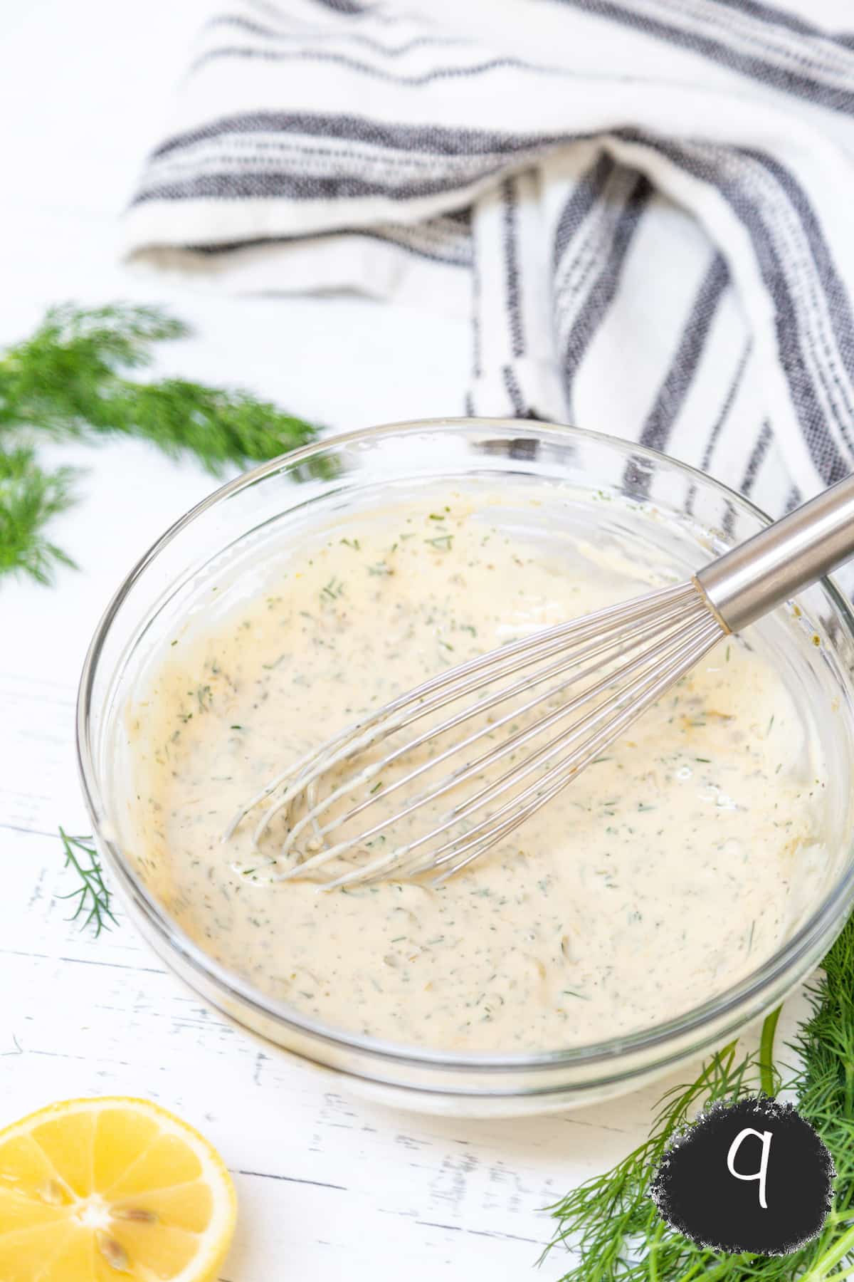 Tartar sauce in a glass bowl with a whisk.