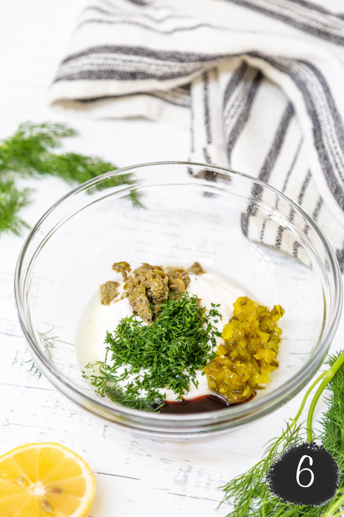 A glass bowl with mayo, chopped pickles, dill, and Worcestershire sauce.