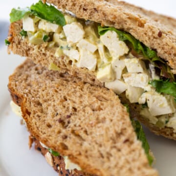 A vegan egg salad sandwich on a white plate.