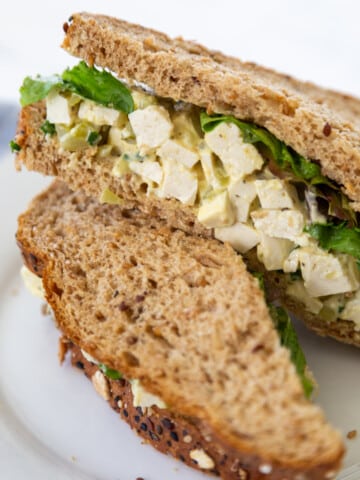 A vegan egg salad sandwich on a white plate.