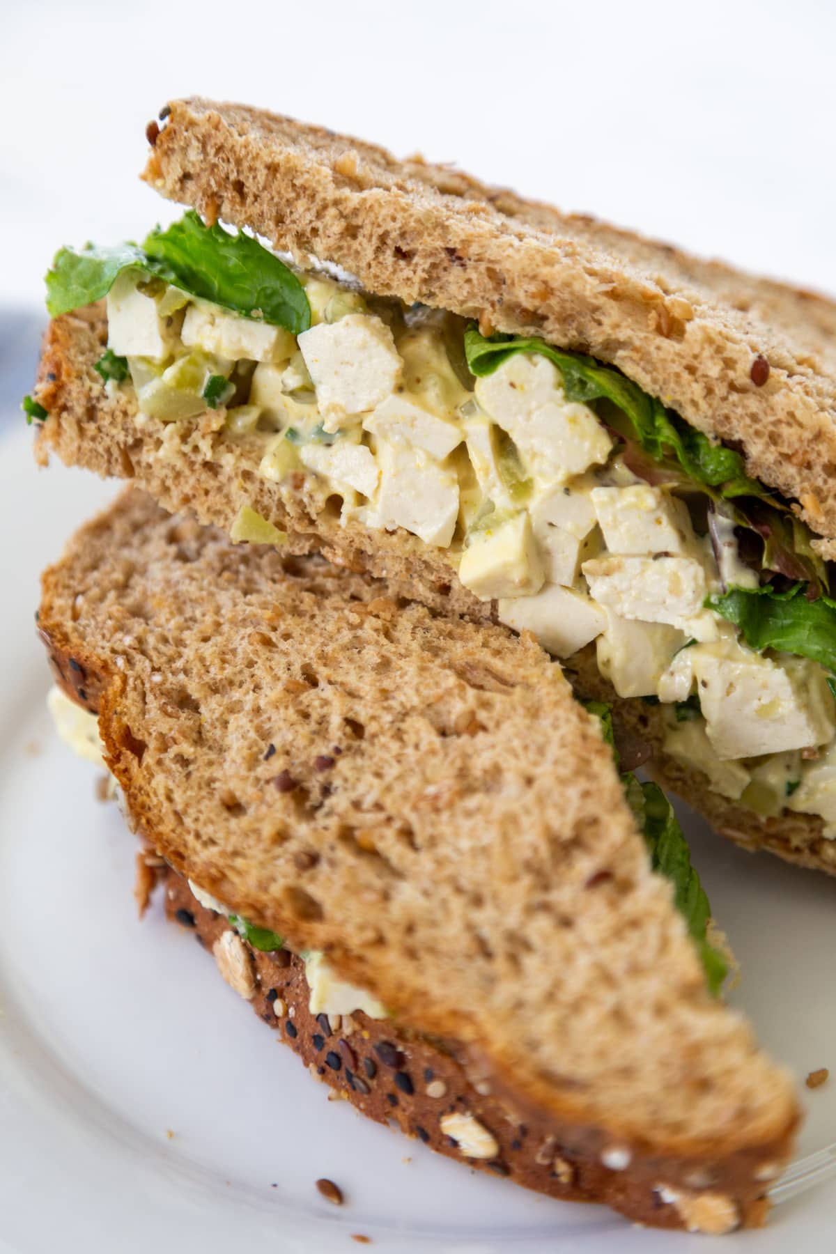 A vegan egg salad sandwich on a white plate.