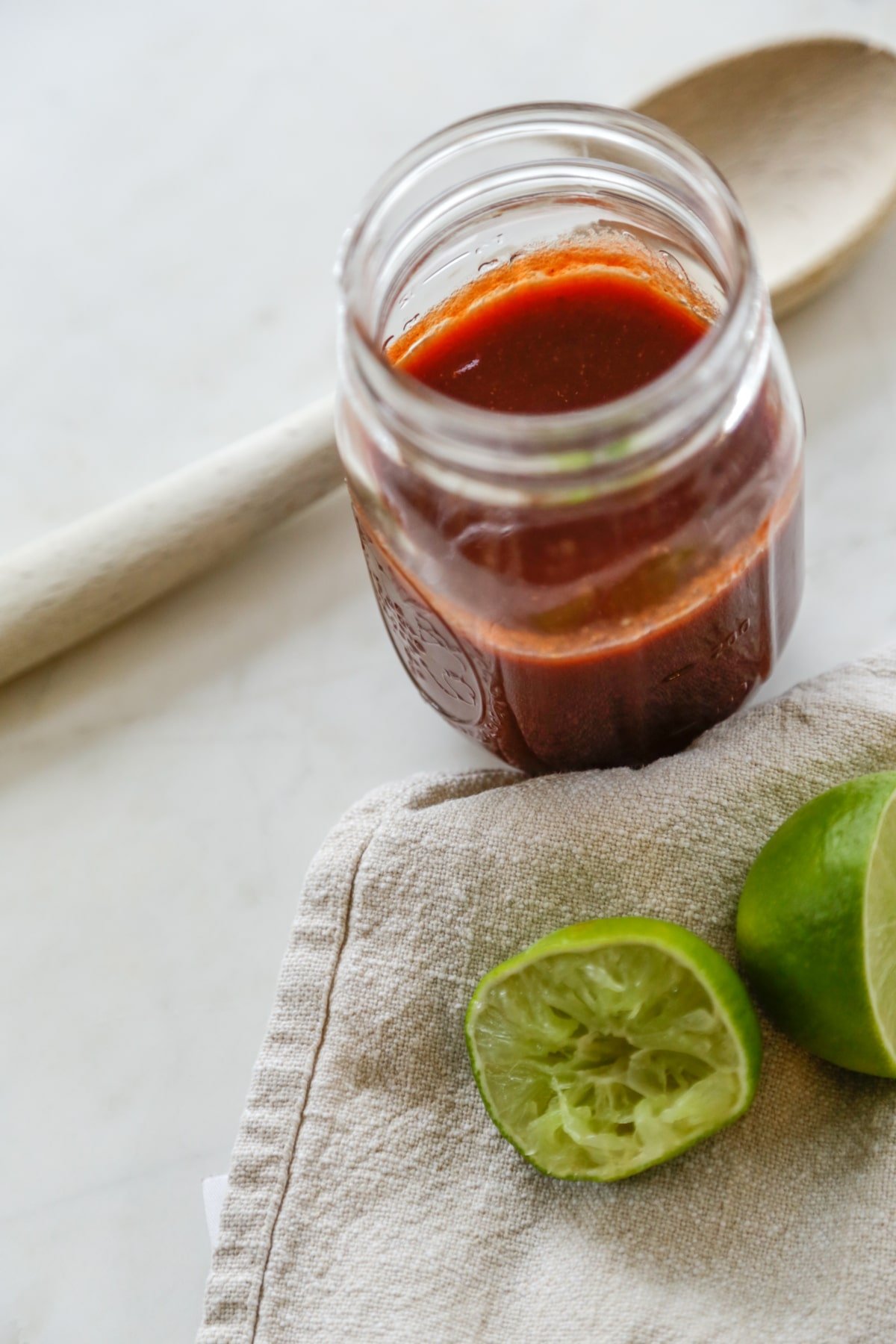 A jar of barbecue sauce with squeezed limes next to it.