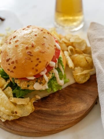 A chickpea burger on a bun with sauce and chips.