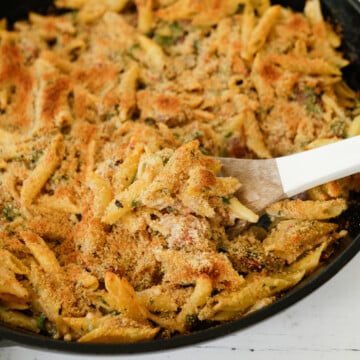 Baked penne pasta in an iron skillet.