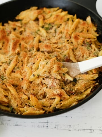 Baked penne pasta in an iron skillet.