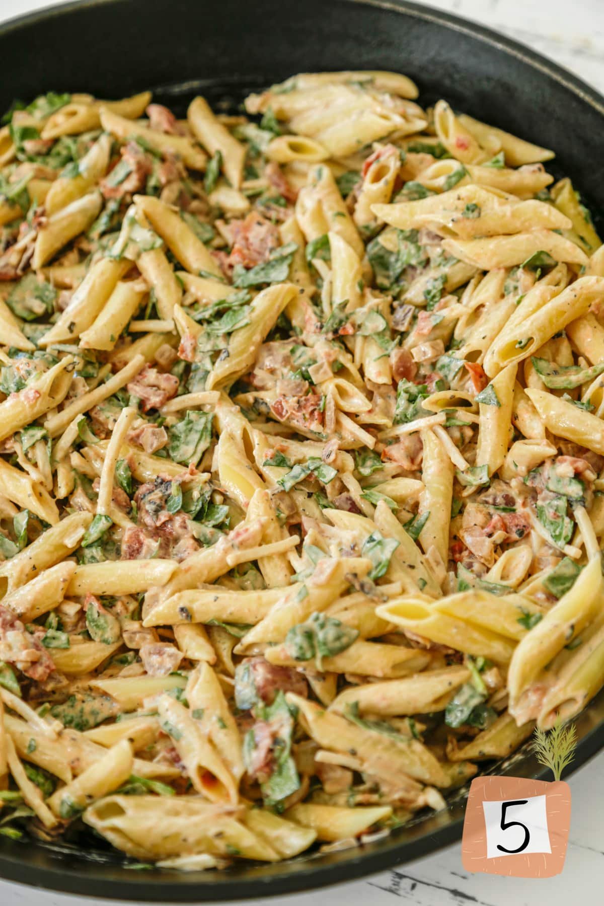 A skillet with pasta, veggies, and cheese.