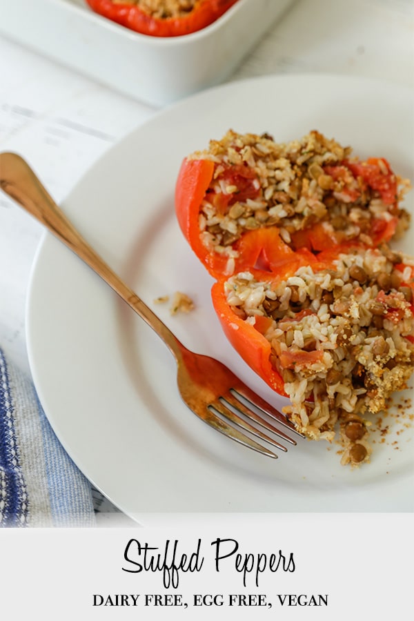 A Pinterest pin for vegan stuffed peppers with a picture of a pepper on a plate.