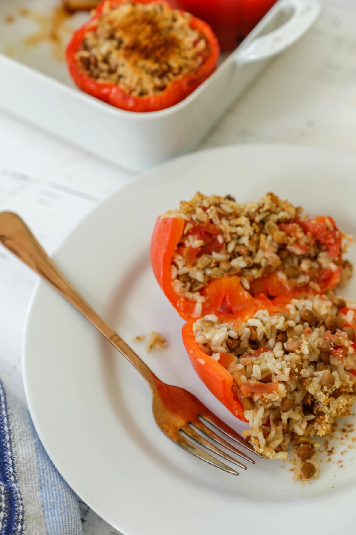 Red bell stuffed pepper on a white plate with a fork.