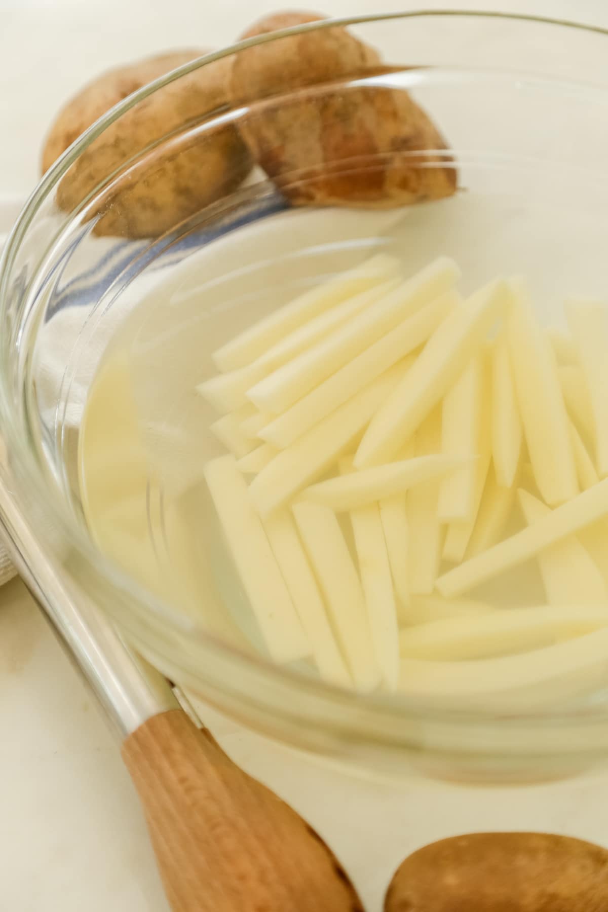 Uncooked French fries soaking in a bowl of water.