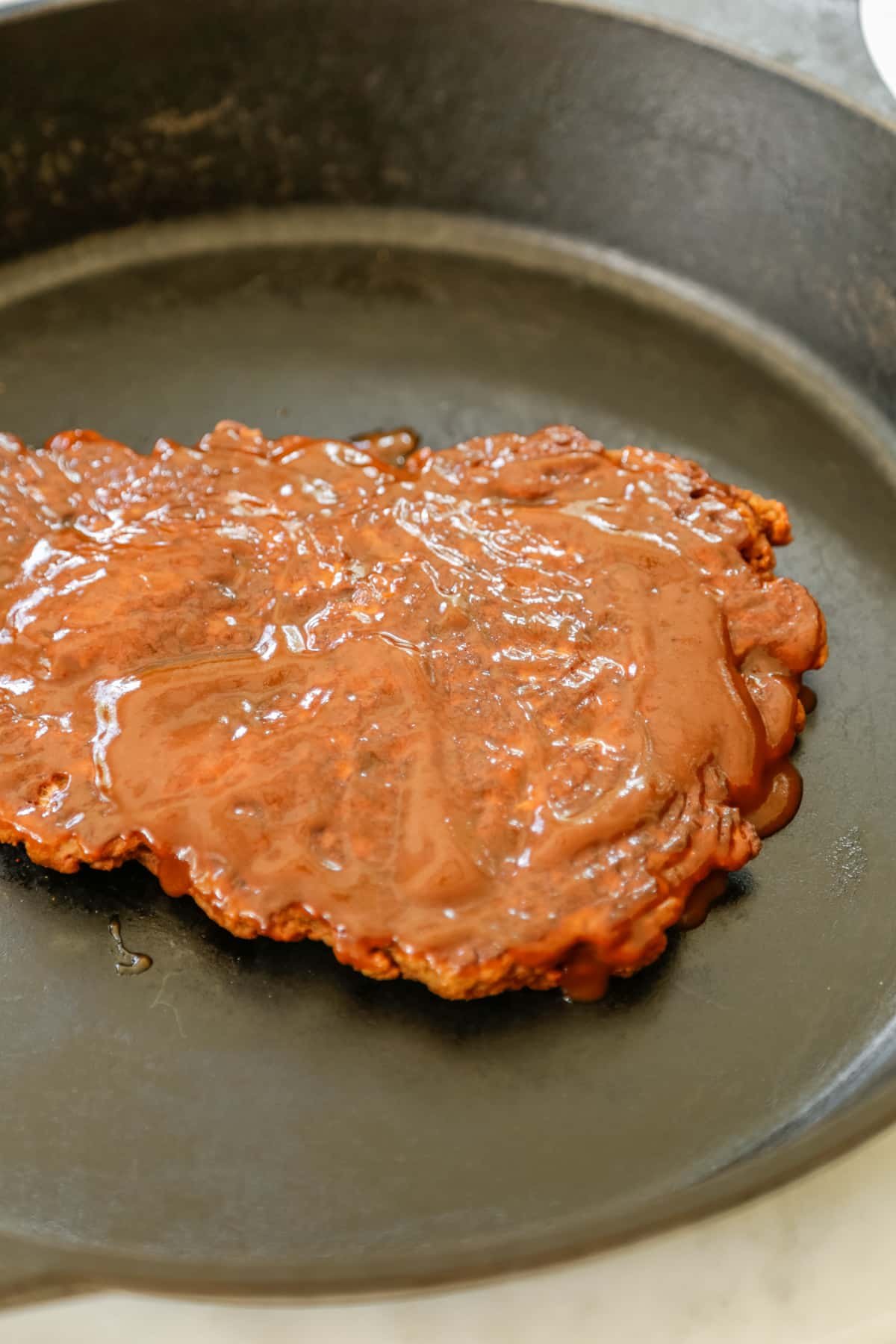 A slab of vegan ribs with bbq sauce in a pan.